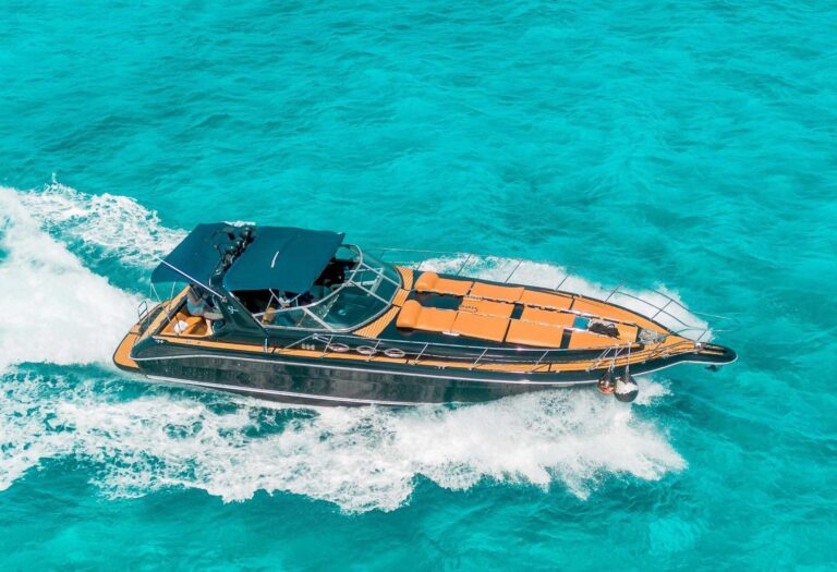 Aerial view of 47 ft Sea Riously black party yacht charter at speed in crystal turquoise Caribbean water near Cancun, distinctive dark hull and teak deck from drone above