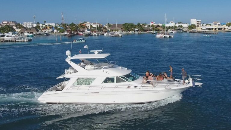 55 ft Sea Ray flybridge yacht rental docked at Marina Puerto Cancun alongside luxury resort, aerial view showing full white hull profile in turquoise water