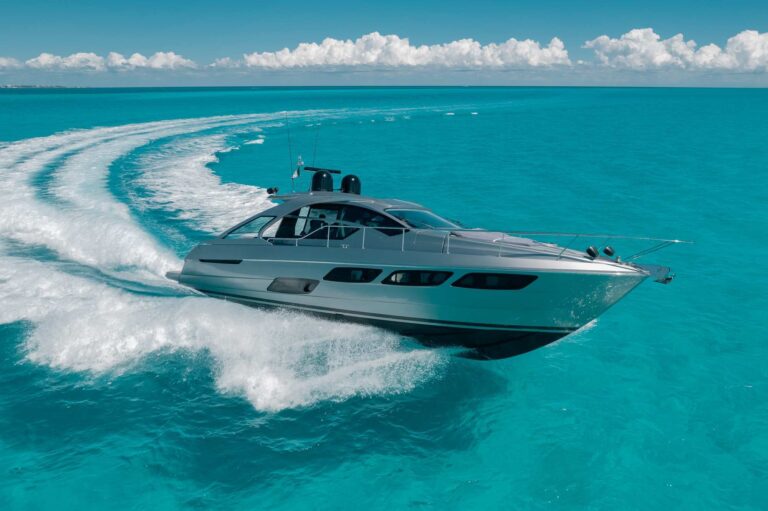 Side profile of 56 ft Pershing luxury sport yacht anchored in brilliant turquoise Cancun waters with city skyline visible, Kantenah yacht charter