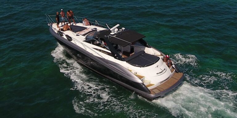 Aerial view of 56 ft Sunseeker Predator black sport yacht cruising at speed with guests on deck, luxury yacht charter Cancun