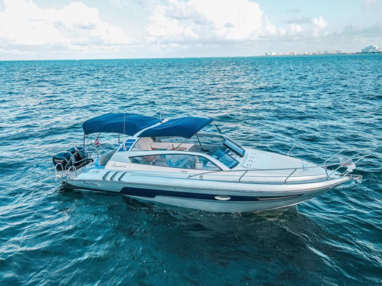 Aerial side view of 34 ft Hanover 305 offshore yacht charter with blue bimini canopy and twin 300HP outboard motors cruising in sparkling turquoise Caribbean water near Cancun