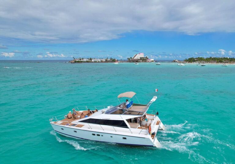 42 ft Cocoon motor catamaran charter cruising turquoise Caribbean near Isla Mujeres landmark, guests lounging on wide teak deck, Cancun rental