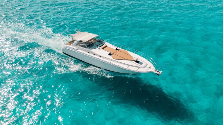 Aerial view of 50 ft Sea Ray Que Paso Ayer luxury yacht charter running at speed through turquoise Caribbean water, white hull and tan foredeck sun pad visible from above