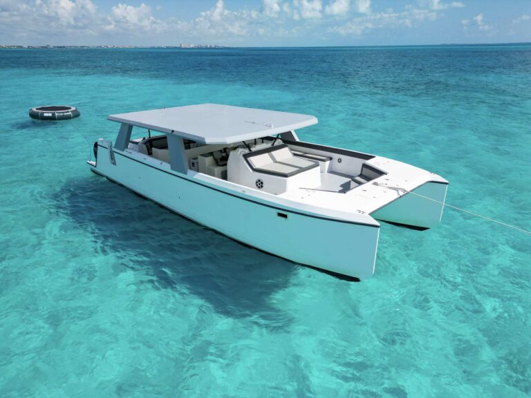 Aerial view of 55 ft MRC catamaran luxury charter anchored in crystal-clear turquoise Caribbean water near Cancun with inflatable trampoline float alongside