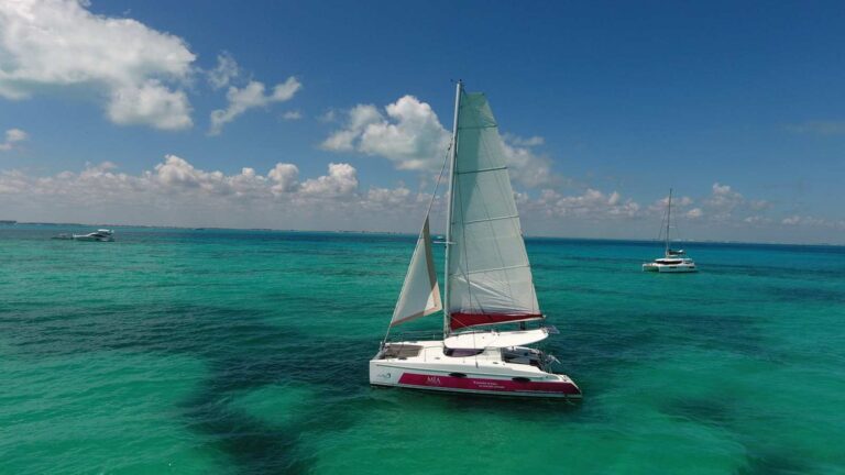 36 ft Fountaine Pajot Mia catamaran sailing with full white sails over turquoise Caribbean water near Isla Mujeres for a luxury day or sunset charter