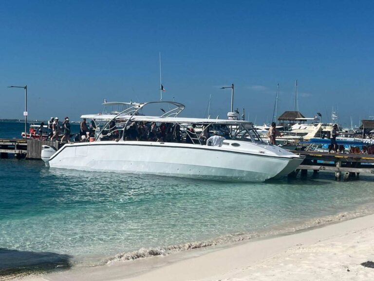 43 ft Martha Luisa private catamaran moored at a sandy Isla Mujeres dock with passengers boarding, turquoise Caribbean water for luxury yacht charter rental