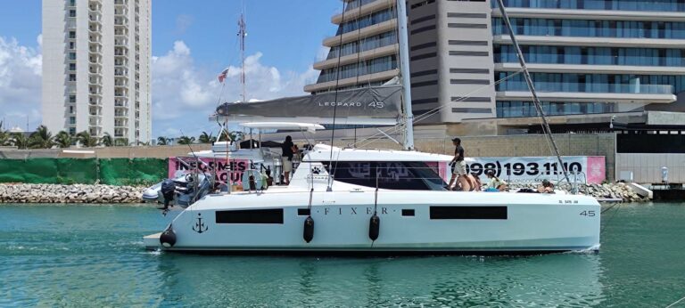 Side view of 45 ft Leopard Fixer luxury catamaran moored at Cancun marina with high-rise hotels behind, ready for yacht charter rental.