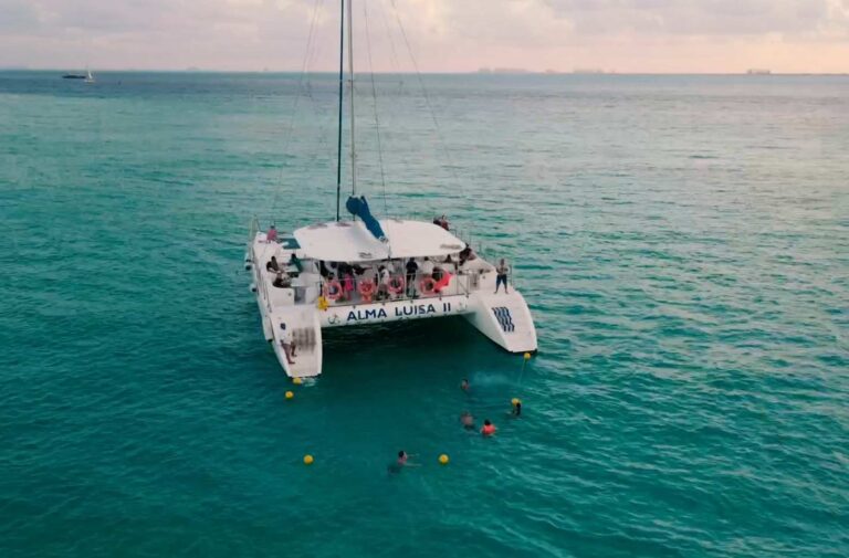 Aerial view of 80 ft Alma Luisa II large catamaran anchored on turquoise Caribbean water near Isla Mujeres with swimmers around for group charter.