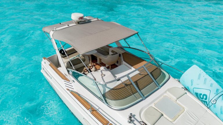 Aerial overhead view of white 35 ft Larson Hakuna Matata charter boat with teak deck and bimini anchored in brilliant turquoise Caribbean water at Progreso Yucatan.