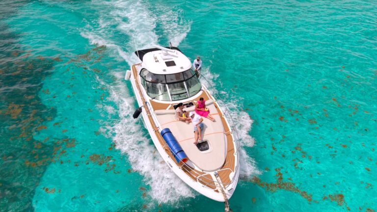 Aerial drone view of 42 ft Sea Ray Mr. Happy sport boat cruising through shallow turquoise Caribbean water with guests relaxing on bow sun pad.