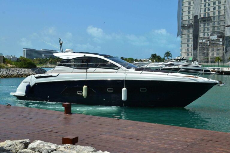 Guest twin cabin of 45 ft Azimut EpiK luxury yacht charter with two single beds, red accent pillows, large porthole, and view of rocky coastline.