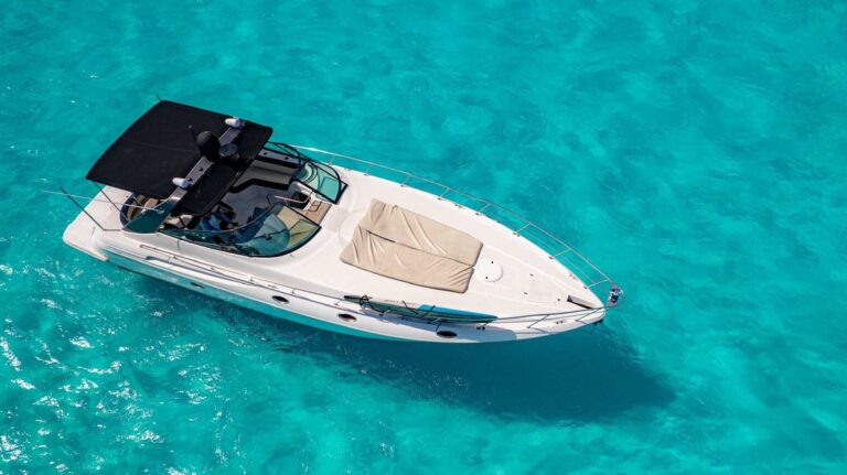 Top-down aerial view of white 46 ft express cruiser yacht rental anchored in crystal-clear turquoise Caribbean water, bow sun pad and cockpit visible.