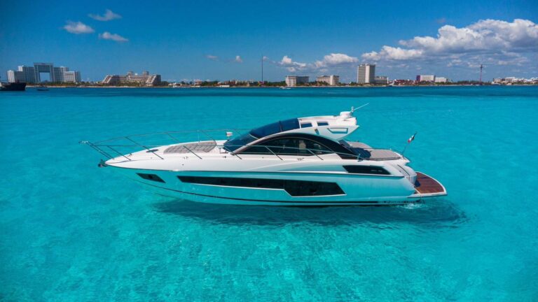 53 ft Sunseeker San Remo luxury yacht charter anchored in crystal-clear turquoise Caribbean water with Cancun hotel zone skyline on horizon.