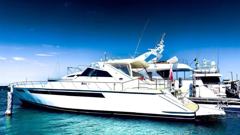 70 ft La Escapada luxury charter yacht moored at Cancun marina, white hull with dark accent stripe, enclosed bridge deck, Caribbean blue water alongside.